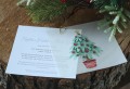 Rozłożone świąteczne zaproszenie i kalka, na nich złoty spinacz